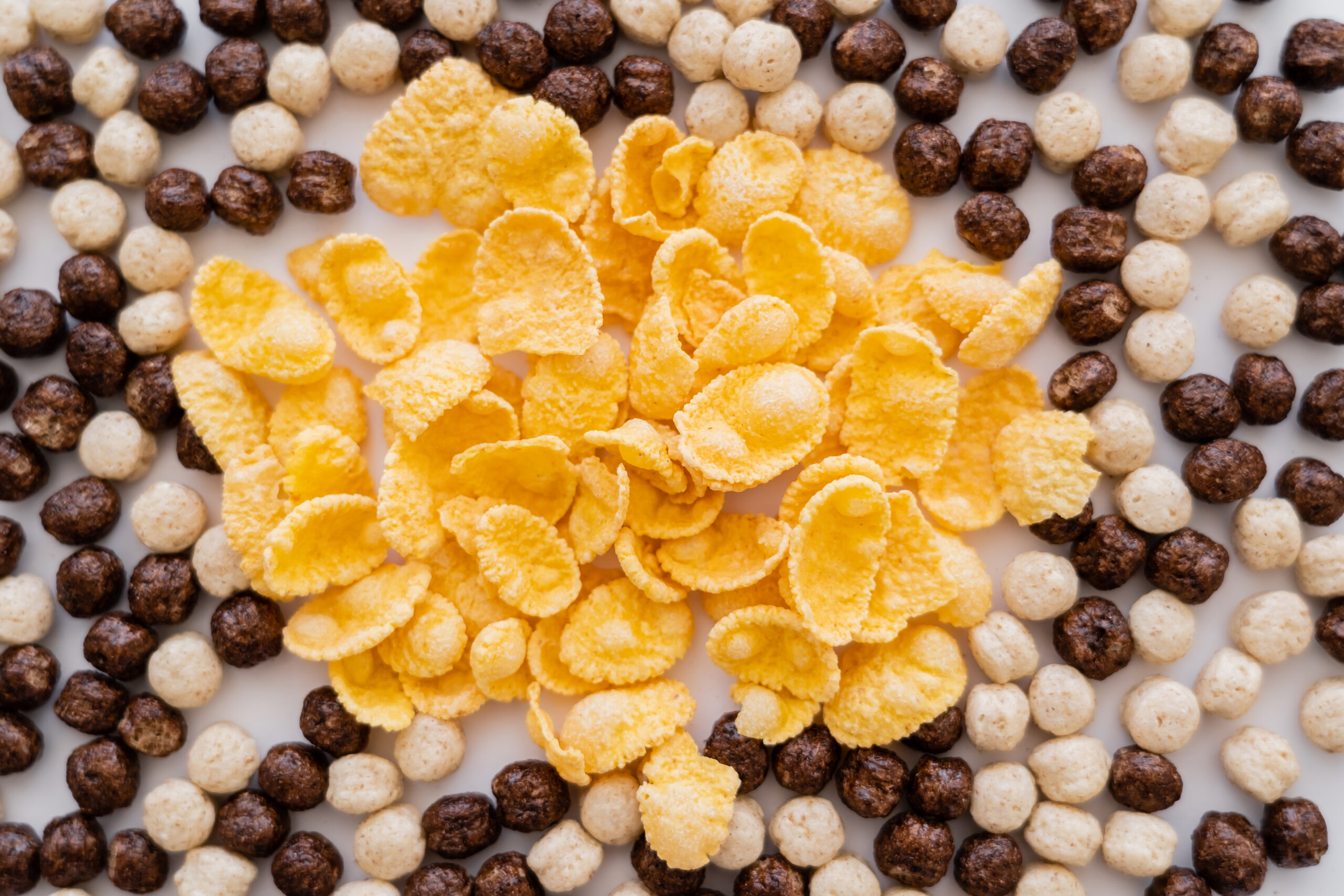 Top View Of Corn Flakes And Cereal Balls With Vanilla And Chocolate Flavors On White